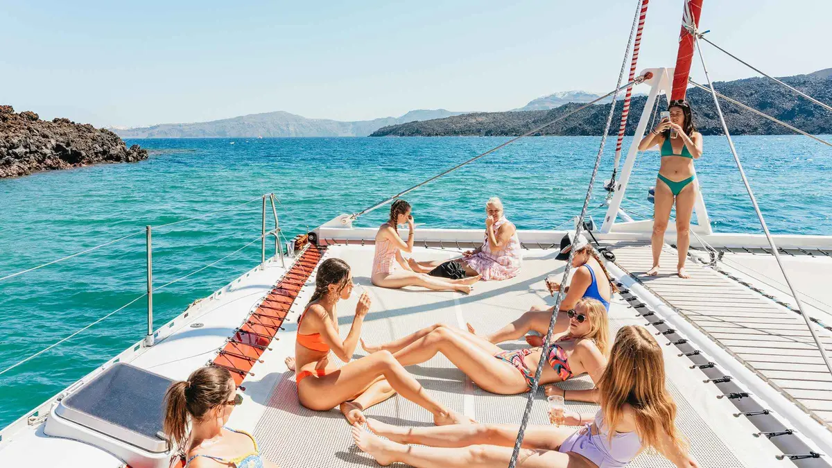 Large catamaran sailing along the caldera on a Santorini catamaran cruise with BBQ dinner and sunset