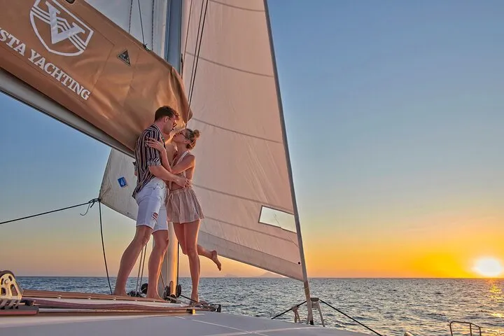 New platinum catamaran off the White Beach cliffs on a Santorini catamaran cruise with BBQ and open bar