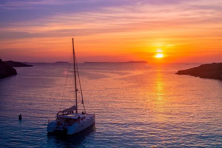 Catamaran sailing toward the sunset on a Santorini catamaran cruise from Vlychada with dinner