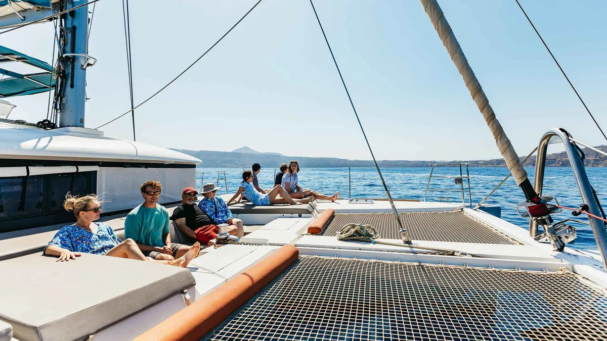 Luxury catamaran under the caldera cliffs on a Santorini catamaran cruise with Greek meal and open bar
