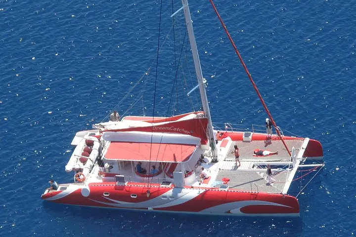 Sailing boat cruising the caldera on a Santorini catamaran cruise with BBQ lunch and drinks