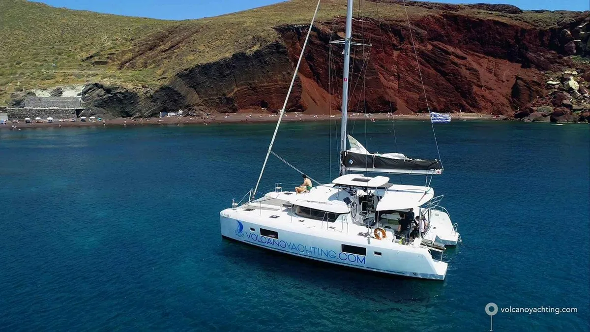 Sailboat under the sunset glow on a Santorini catamaran cruise with dinner and swim stops
