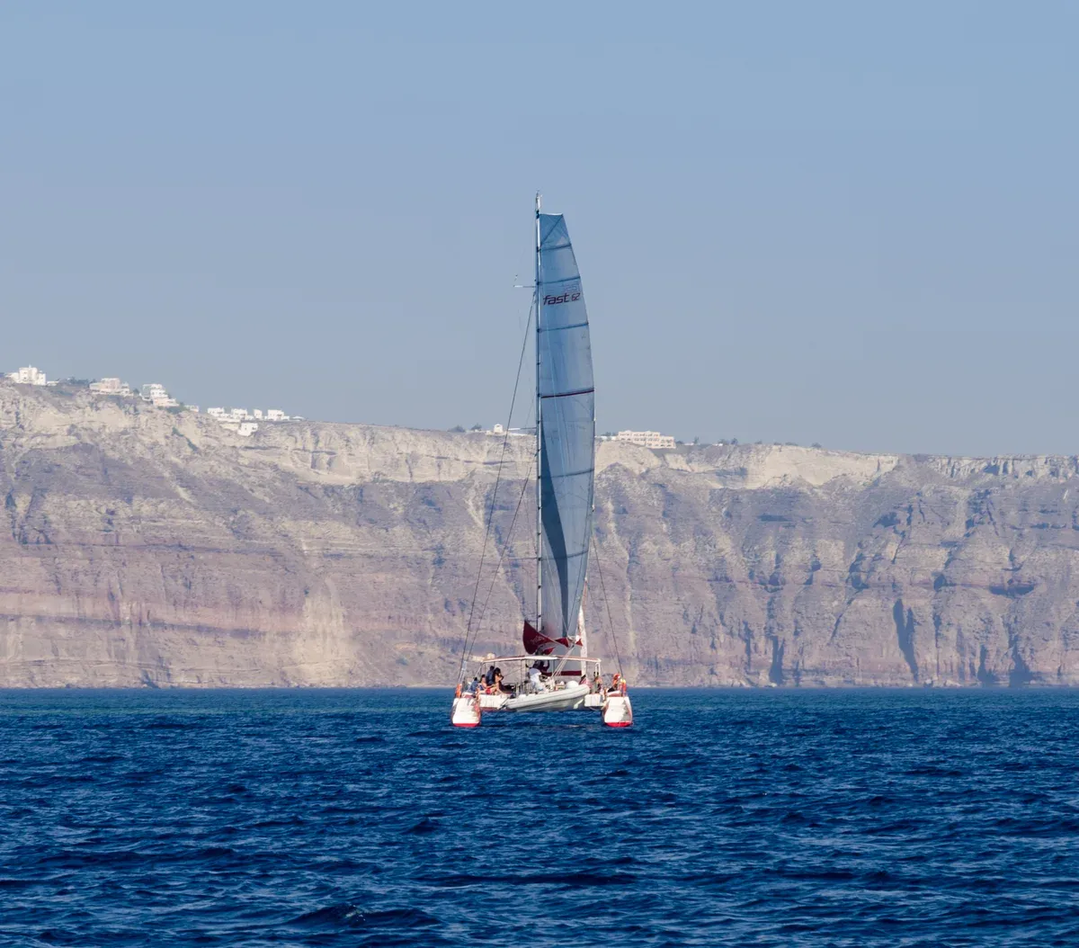 Sailing catamaran in the caldera near Palea Kameni on a Santorini catamaran cruise