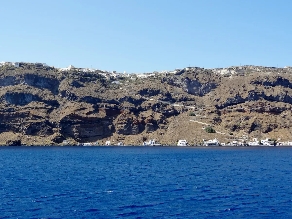 Thirasia caldera cliff with Korfos harbor at its foot on a Santorini catamaran cruise with a Thirassia stop