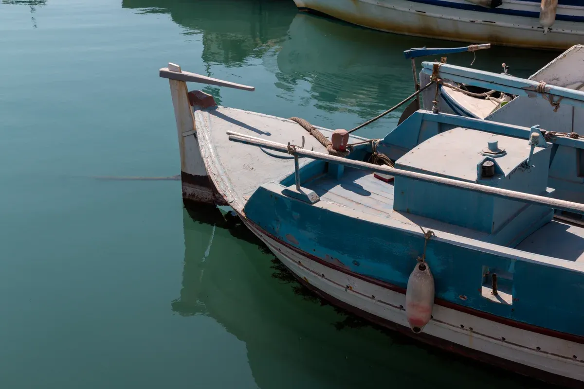 Fishing boat moored in the green water of Vlychada marina on Santorini, near Santorini catamaran cruise departures